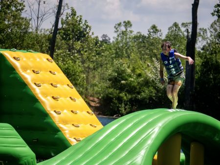 Indian Springs Campground & Water Park - Family enjoying the new Splash Springs Floating Water Park with water slide, beach area, and scenic fishing lakes in a serene forest setting. Perfect for camping, fishing, and water fun near Fort Wayne.